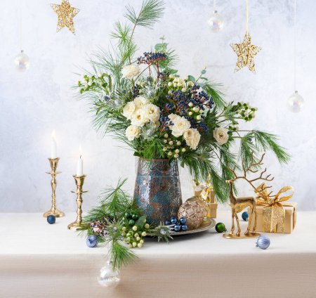 Photo for Christmas decorations, candles, gift boxes and flower bouquet. Winter arrangement with roses, fir branches, winter berries. Christmas still life. - Royalty Free Image