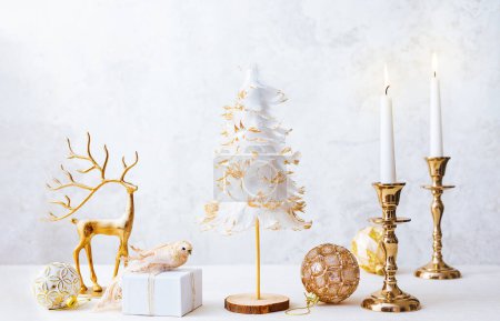 Téléchargez les photos : Noël hiver nature morte avec des bougies allumées, boîte cadeau et décorations de Noël sur fond de lumière pastel. Composition de Noël pour la maison - en image libre de droit