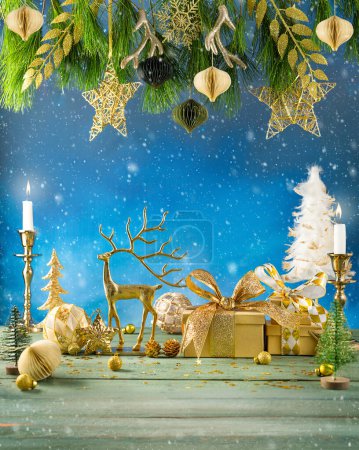 Photo for Christmas or New Year festive composition. Fir branches, candles, gold Christmas decorations,balls, deer and gift boxes on wooden table. - Royalty Free Image