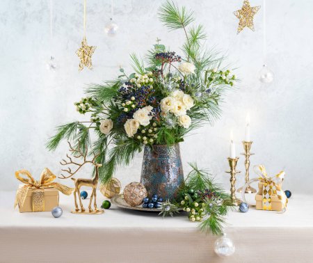Photo for Christmas decorations, candles, gift boxes and flower bouquet. Winter arrangement with roses, fir branches, winter berries. Christmas still life. - Royalty Free Image