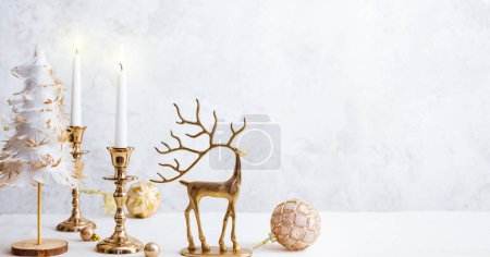 Photo for Cozy still life with burning candles, figure of deer and Christmas decorations on pastel light background. Christmas composition for home interio - Royalty Free Image