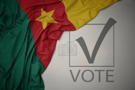 Foto de Ondeando colorida bandera nacional de camerún sobre un fondo gris con voto de texto. concepto de elección. Ilustración 3D - Imagen libre de derechos