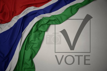 Foto de Ondeando colorida bandera nacional de gambia sobre un fondo gris con voto de texto. concepto de elección. Ilustración 3D - Imagen libre de derechos