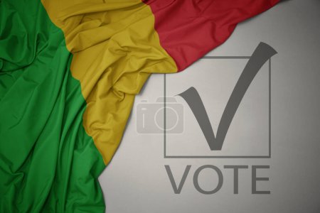 Foto de Ondeando colorida bandera nacional de Malí sobre un fondo gris con voto de texto. concepto de elección. Ilustración 3D - Imagen libre de derechos