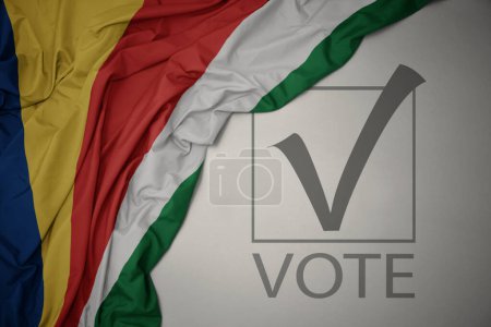 Foto de Ondeando colorida bandera nacional de seychelles sobre un fondo gris con voto de texto. concepto de elección. Ilustración 3D - Imagen libre de derechos