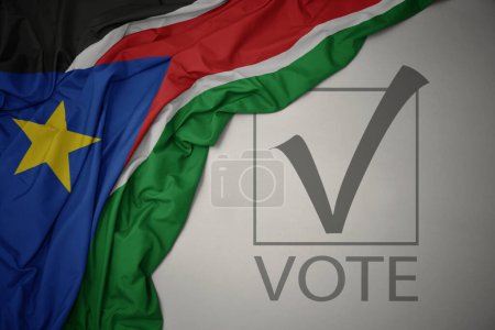 Foto de Ondeando colorida bandera nacional del sur de Sudán sobre un fondo gris con voto de texto. concepto de elección. Ilustración 3D - Imagen libre de derechos