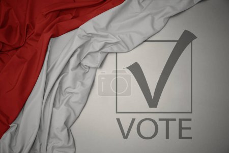 Foto de Ondeando colorida bandera nacional de indonesia sobre un fondo gris con voto de texto. concepto de elección. Ilustración 3D - Imagen libre de derechos