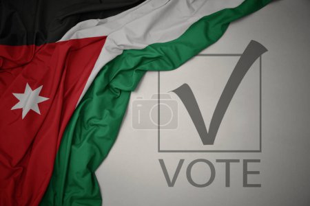 Foto de Ondeando colorida bandera nacional de Jordania sobre un fondo gris con voto de texto. concepto de elección. Ilustración 3D - Imagen libre de derechos