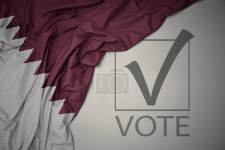 Foto de Ondeando colorida bandera nacional de qatar sobre un fondo gris con voto de texto. concepto de elección. Ilustración 3D - Imagen libre de derechos