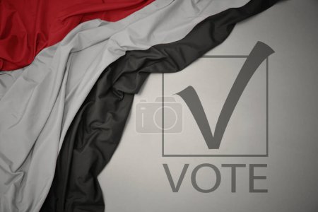 Foto de Ondeando colorida bandera nacional de yemen sobre un fondo gris con voto de texto. concepto de elección. Ilustración 3D - Imagen libre de derechos