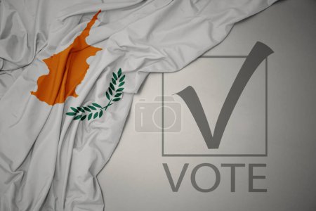 Foto de Ondeando colorida bandera nacional de cyprus sobre un fondo gris con voto de texto. concepto de elección. Ilustración 3D - Imagen libre de derechos