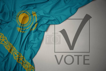 Foto de Ondeando colorida bandera nacional de Kazajstán sobre un fondo gris con voto de texto. concepto de elección. Ilustración 3D - Imagen libre de derechos