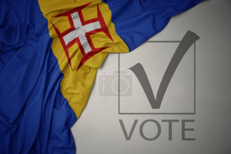 Foto de Ondeando colorida bandera nacional de Madeira sobre un fondo gris con voto de texto. concepto de elección. Ilustración 3D - Imagen libre de derechos