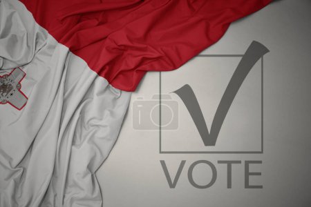 Foto de Ondeando colorida bandera nacional de malta sobre un fondo gris con voto de texto. concepto de elección. Ilustración 3D - Imagen libre de derechos