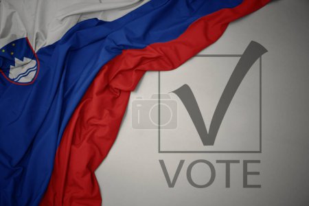 Foto de Ondeando colorida bandera nacional de slovenia sobre un fondo gris con voto de texto. concepto de elección. Ilustración 3D - Imagen libre de derechos