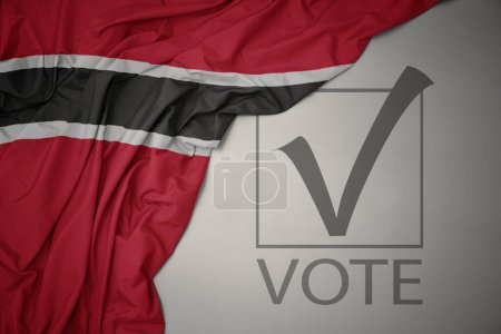 Foto de Ondeando colorida bandera nacional de trinidad y tobago sobre un fondo gris con voto de texto. concepto de elección. Ilustración 3D - Imagen libre de derechos
