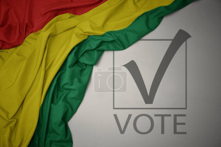Foto de Ondeando colorida bandera nacional de Bolivia sobre un fondo gris con voto de texto. concepto de elección. Ilustración 3D - Imagen libre de derechos