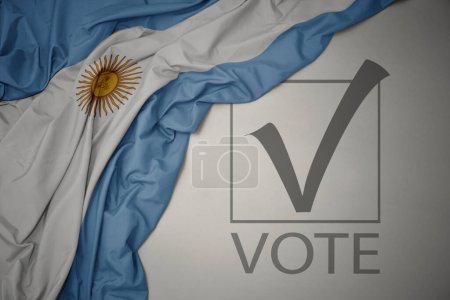 Foto de Ondeando colorida bandera nacional de Argentina sobre un fondo gris con voto de texto. concepto de elección. Ilustración 3D - Imagen libre de derechos