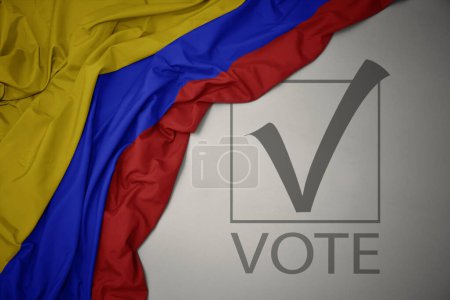 Foto de Ondeando colorida bandera nacional de Colombia sobre un fondo gris con voto de texto. concepto de elección. Ilustración 3D - Imagen libre de derechos