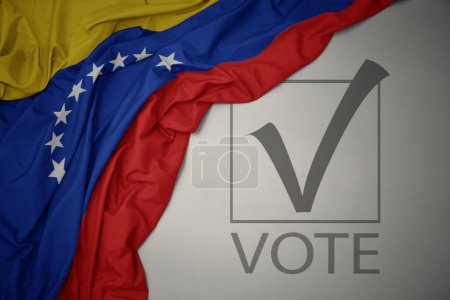 Foto de Ondeando colorida bandera nacional de venezuela sobre un fondo gris con voto de texto. concepto de elección. Ilustración 3D - Imagen libre de derechos