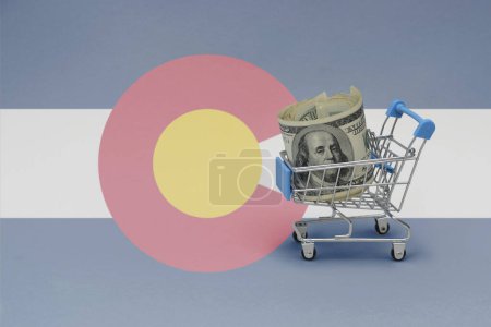 Foto de Cesta de la compra del metal con el billete de dinero del dólar grande en el fondo de la bandera del estado de Colorado. concepto de cesta de consumo. ilustración 3d - Imagen libre de derechos