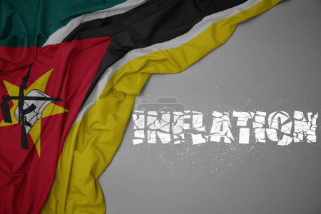 Foto de Ondeando colorida bandera nacional de Mozambique sobre un fondo gris con la inflación de texto roto. concepto. ilustración 3d - Imagen libre de derechos