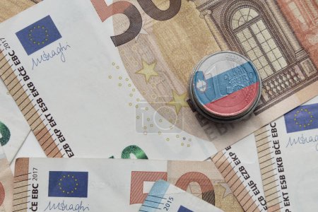 moneda en euros con bandera nacional colorida de slovenia en el fondo de los billetes en euros
