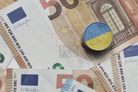 Foto de Moneda en euros con bandera nacional colorida de Ucrania en el fondo de los billetes en euros - Imagen libre de derechos