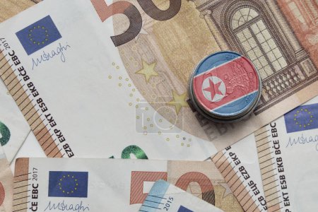 Foto de Moneda en euros con bandera nacional colorida de Corea del Norte sobre el fondo de los billetes en euros - Imagen libre de derechos