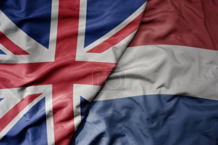 big waving national colorful flag of great britain and national flag of netherlands . macro