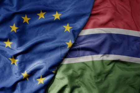 Foto de Gran ondeando bandera colorida nacional realista de la unión europea y bandera nacional de gambia. macro - Imagen libre de derechos