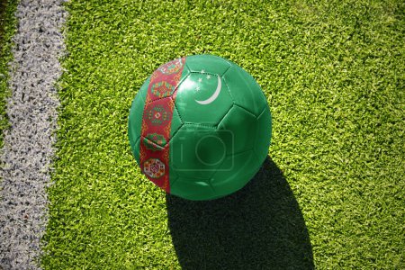 Téléchargez les photos : Ballon de football avec le drapeau national du Turkménistan sur le terrain vert près de la ligne blanche - en image libre de droit
