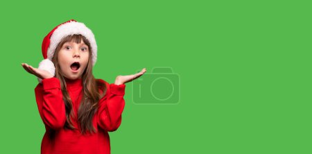 Photo for Merry Christmas and New Year. Very emotional surprised girls in a red Santa hat waiting for Christmas gifts. The child is overjoyed. Promotions, discounts, gifts. High quality photo - Royalty Free Image