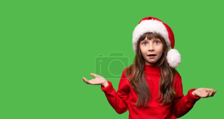 Photo for Merry Christmas and New Year. Very emotional surprised girls in a red Santa hat waiting for Christmas gifts. The child is overjoyed. Promotions, discounts, gifts. High quality photo - Royalty Free Image