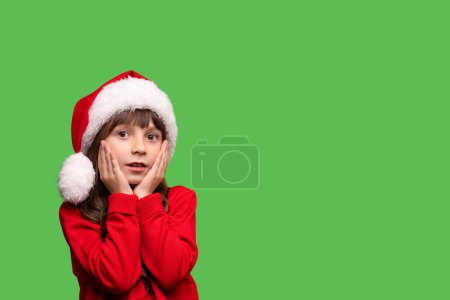 Foto de Feliz Navidad y Año Nuevo. Retrato de una chica sorprendida en un sombrero de Santa Claus rojo esperando regalos de Navidad. Foto de alta calidad - Imagen libre de derechos