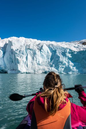 Foto de Mujer joven Kayak Mosevatnet Lake con el glaciar Folgefonna en el fondo, Visitando Noruega - Imagen libre de derechos