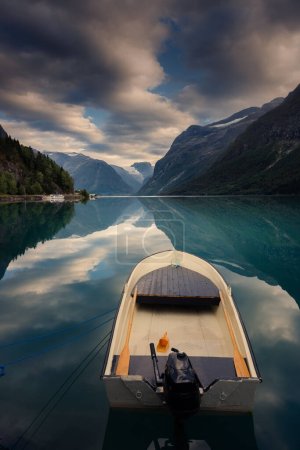 Norwegian mountain lake with boat, clouds, and stunning reflections of nature.