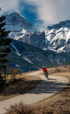 A woman rides a bike on the Legacy Trail in Canmore, Alberta, Canada.