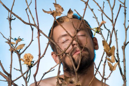 Foto de Retrato de un tipo en ramas secas de una rosa - Imagen libre de derechos