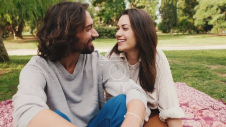 Photo for Happy smiling couple talking while sitting on blanket in park. Close-up - Royalty Free Image