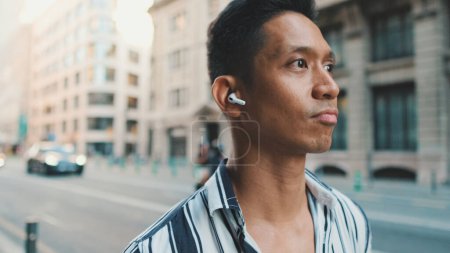 Photo for Young man walks next to the road and listens to music with headphones - Royalty Free Image
