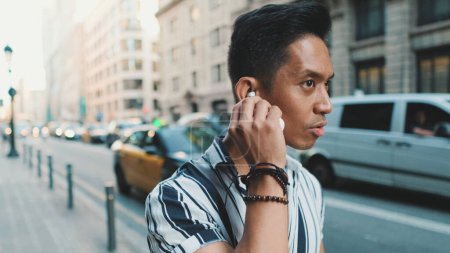 Photo for Young man walks next to the road and listens to music with headphones - Royalty Free Image