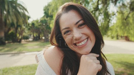 Photo for Close up, young woman looks at the camera and smiles in the park - Royalty Free Image