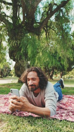 Photo for Young man relaxing in the park and using mobile phone - Royalty Free Image