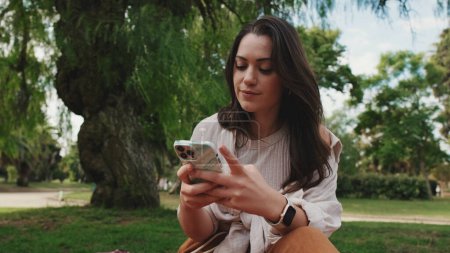 Photo for Close up, young woman using phone in the park - Royalty Free Image
