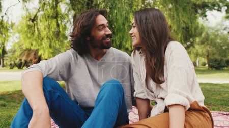 Photo for Happy smiling couple talking while sitting on blanket in park. Close-up - Royalty Free Image