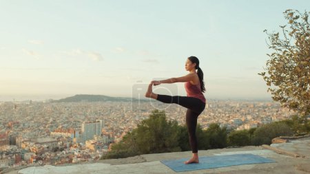 Foto de Chica practica yoga se para en una pierna en el mirador al amanecer - Imagen libre de derechos