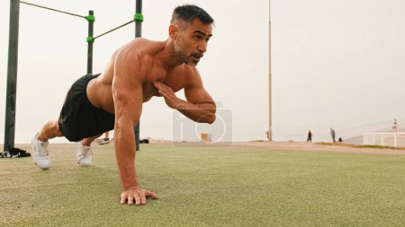Homme musculaire d'âge moyen faisant pousser vers le haut des exercices à l'extérieur