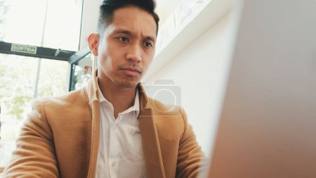 Photo for Close up, young handsome businessman wearing beige suit working with laptop in cafe - Royalty Free Image