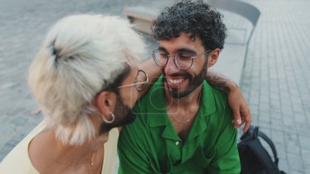 Close up, homosexual loving couple hugging chatting animatedly on street